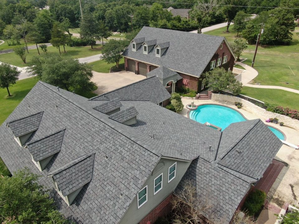 Close aerial of a complex gray shingle roof beside a pool
