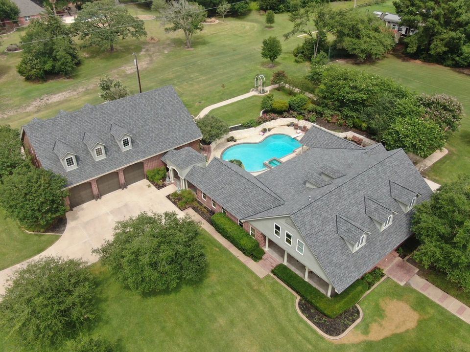 Aerial view of a large home with a new gray architectural shingle roof and a backyard pool